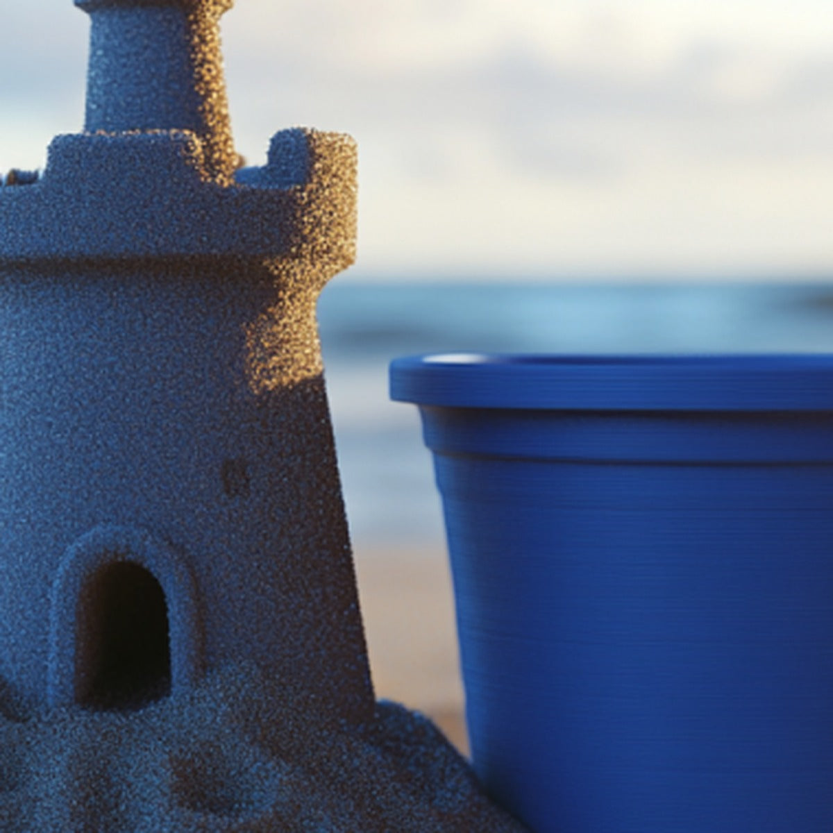 Blue 3D-printed sandcastle and bucket on sunny beach — outdoor/heat use