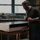 Maker working next to the Bambu Lab R1 laser cutter in a home workshop