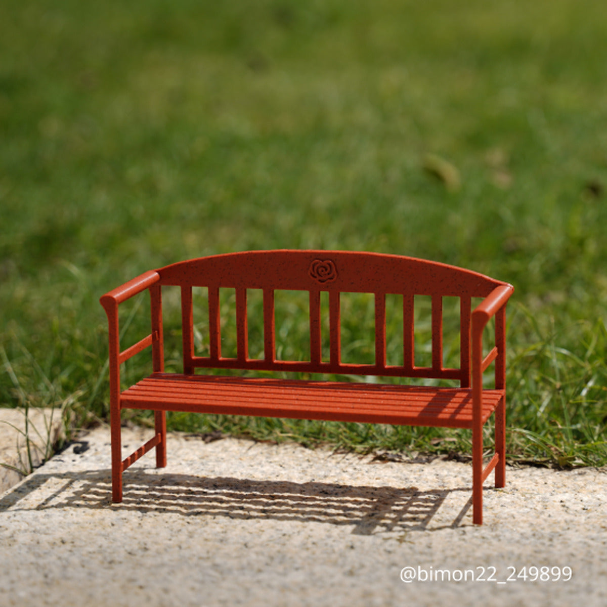 Red Granite miniature park bench on outdoor stone with grass bokeh
