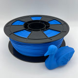 A spool of bright blue 3D printing filament with a black plastic hub, shown next to a small blue duck-shaped printed object on a light gray background.