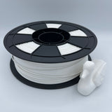A spool of white 3D printer filament with a black plastic core, shown next to a small white printed duck figurine on a light gray background.