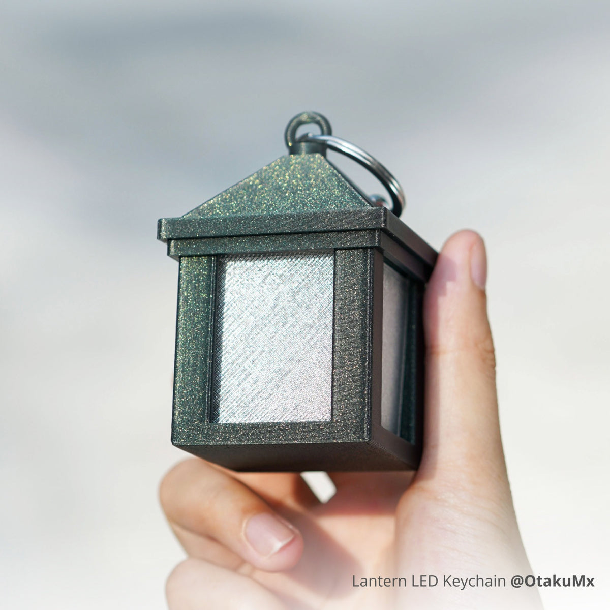 Lantern keychain 3D printed in green Bambu PLA Galaxy, held in a hand