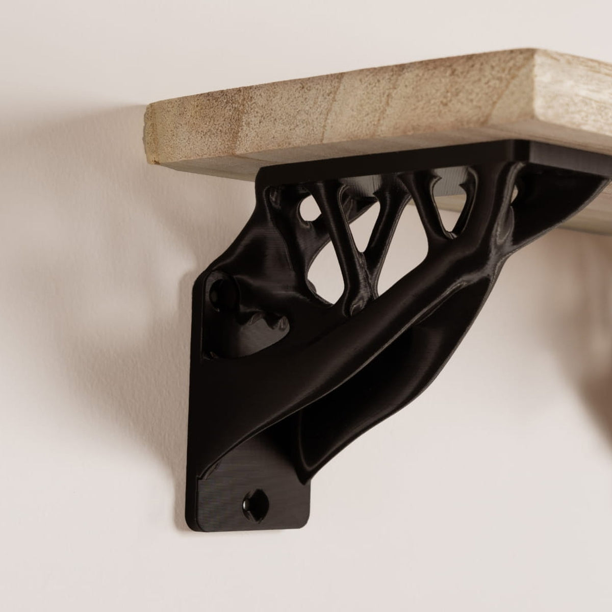 Black shelf bracket 3D printed in Bambu PLA Tough+ holding a wood shelf